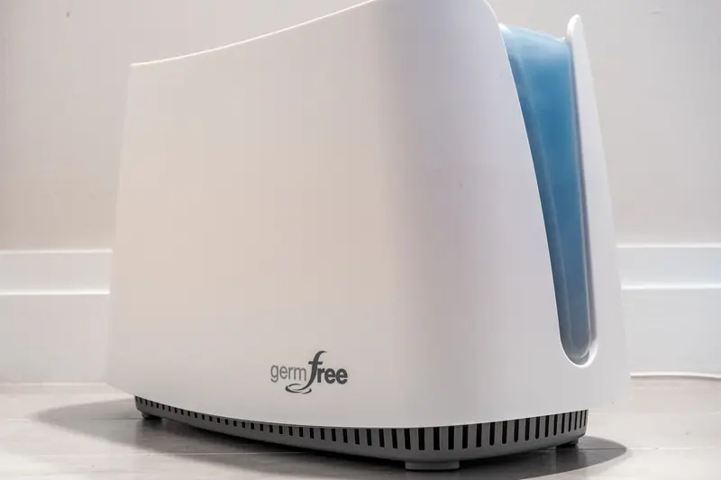 A small white portable humidifier on a table, its translucent blue water tank half full